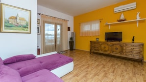 A room with a bed, wooden floor, a TV on a wooden cabinet, and a painting on the wall. - Apartments Amulic (Duce)