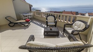 A balcony with wicker furniture, a table, and a view of the sea. - Apartments and Rooms LEA (Bol)