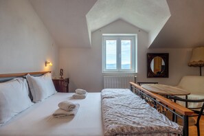 A bedroom with a bed, a wooden bench, a table, a chair, a window, and a mirror. - Apartments and Rooms LEA (Bol)
