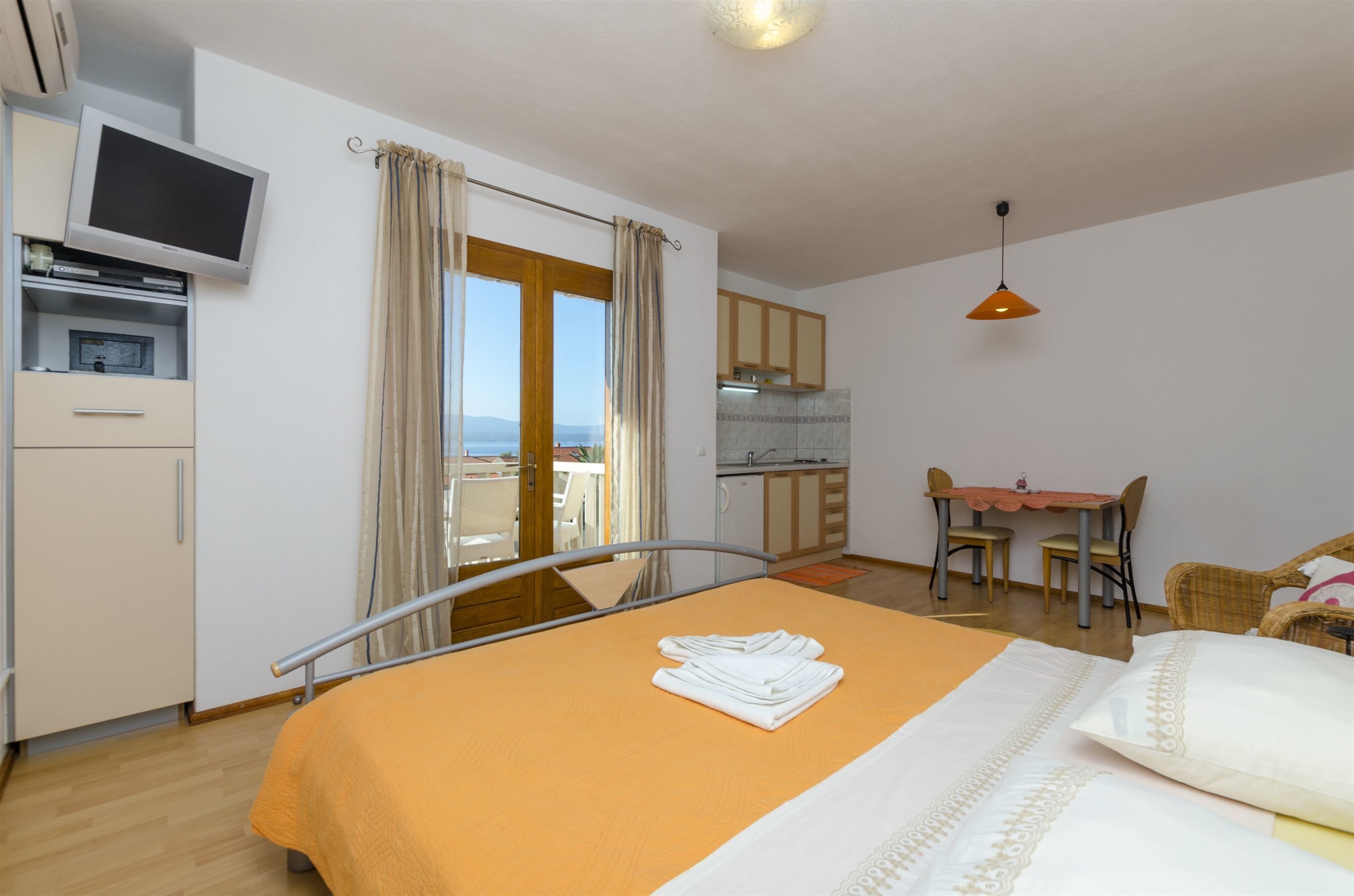 Ein Hotelzimmer mit Bett, Fernseher, Küchenzeile und Essbereich.