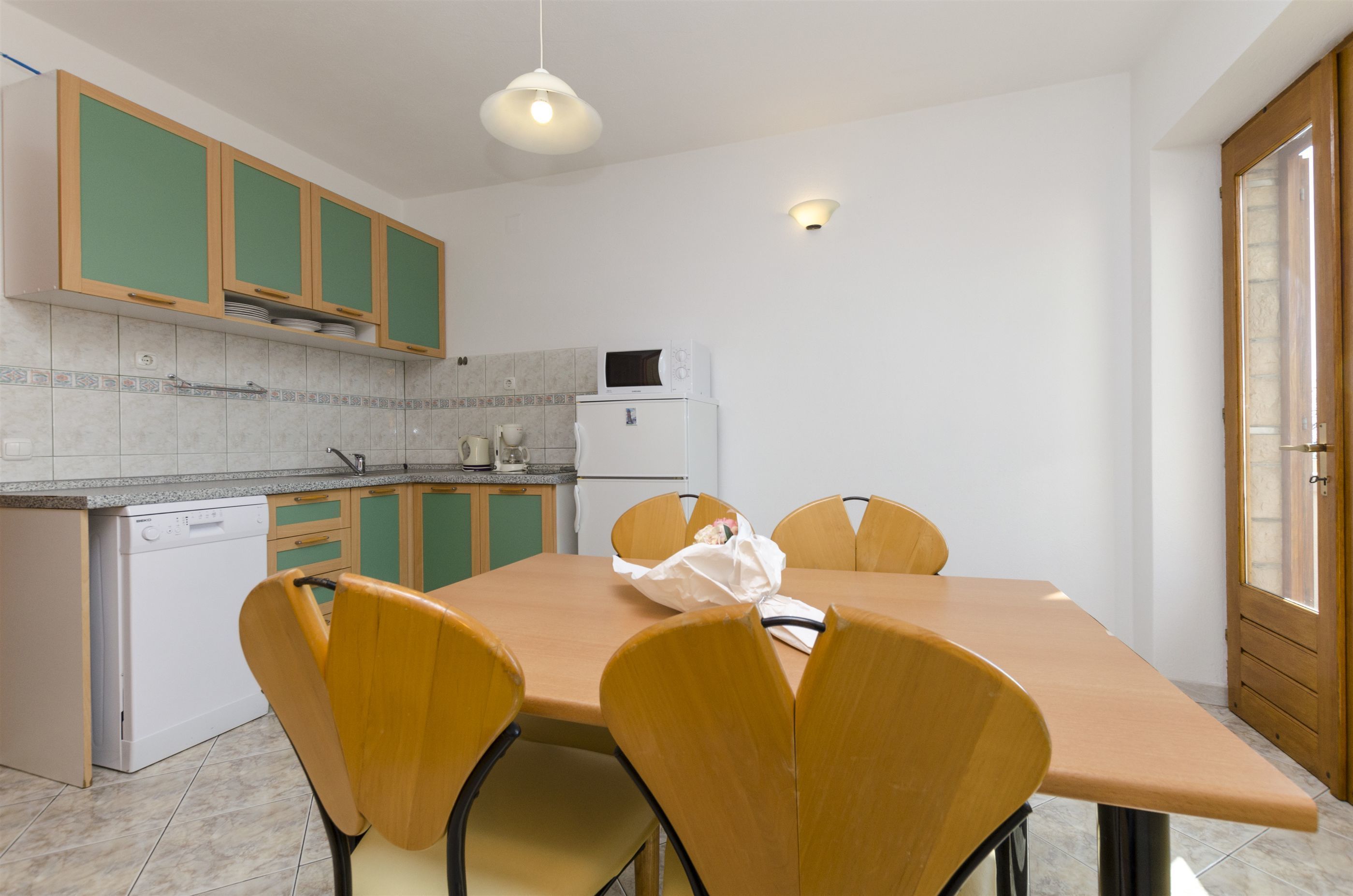 A modern kitchen with a dining table, chairs, and basic appliances.
