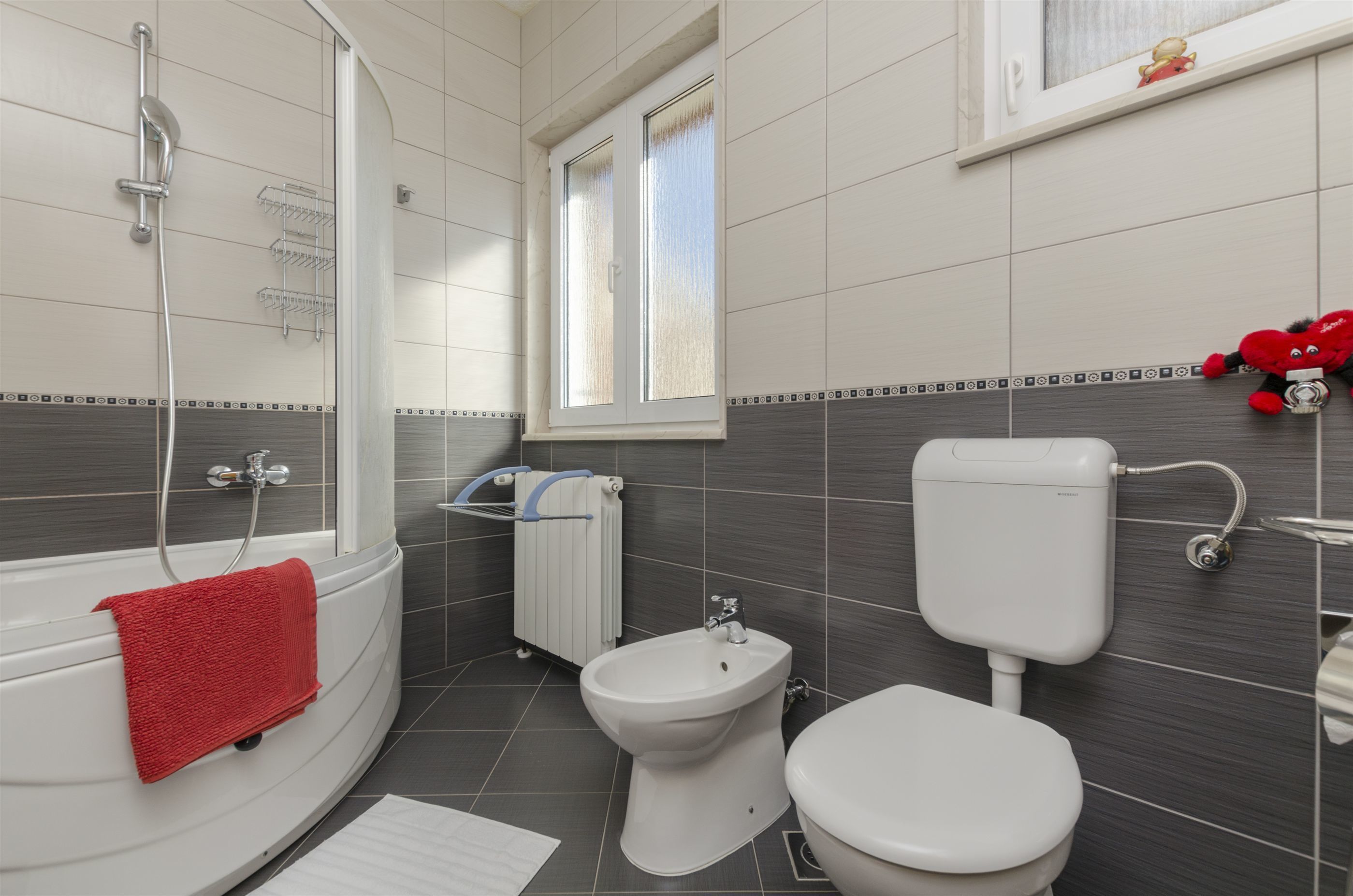Un baño con bañera, bidé, inodoro y ventana.