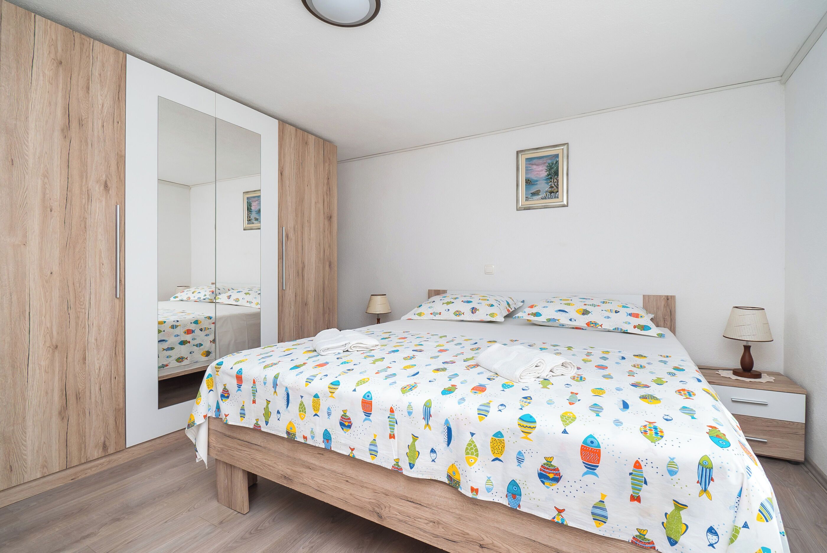 A bedroom with a bed, nightstands, a mirror, and a wardrobe.