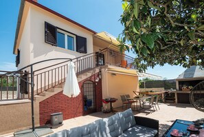 A two-story house with a balcony, outdoor seating area, and a staircase. - Apartments Hrvatic (Rogoznica)