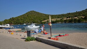 A beach with boats, a sandy shore, and a hill in the background. - Apartments Hrvatic (Rogoznica)