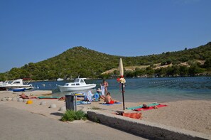 A beach with boats, a sandy shore, and a hill in the background. - Apartments Hrvatic (Rogoznica)