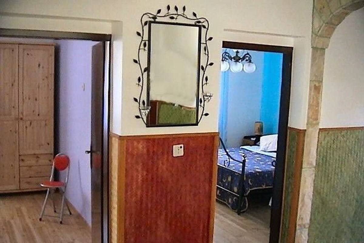 Una habitación con un armario de madera, un espejo, una cama con cabecera azul y una silla.