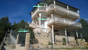 A multi-story building with balconies, a wrought iron gate, and a stone staircase.