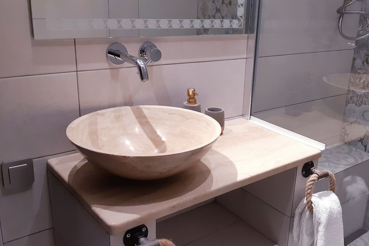 Une salle de bain avec un grand lavabo beige, un miroir au-dessus et un porte-serviettes sur lequel est posée une serviette blanche.