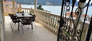 Ein Balkon mit Tisch und Stühlen, Blick auf ein Gewässer und eine weiße Brüstung.