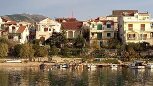Una propiedad frente al agua con varias construcciones, un muelle con barcos y montañas al fondo.