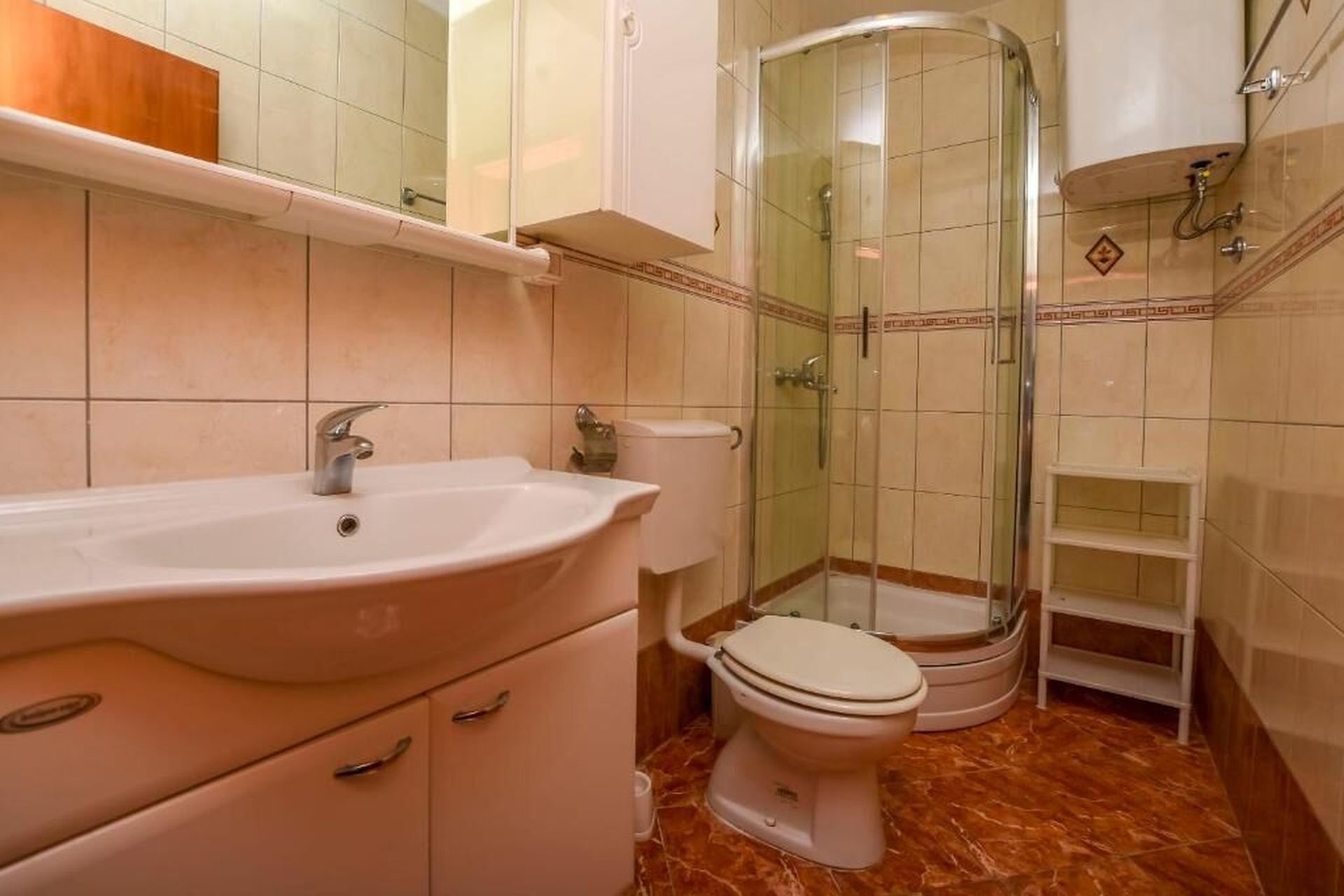 Baño con lavabo, inodoro y ducha con mampara de vidrio.