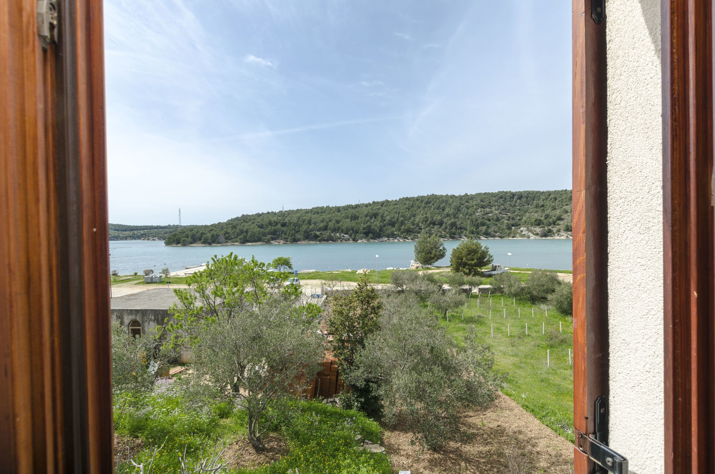 A view from a window overlooking a lake, trees, and a distant hill.