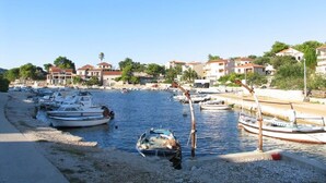 Una marina con diverse imbarcazioni ormeggiate, una spiaggia sabbiosa e edifici sullo sfondo.