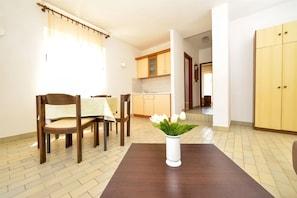 A dining area with a wooden table, chairs, and a vase with flowers.