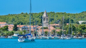 Uma marina com barcos atracados, uma torre e casas ao fundo.