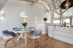 Un comedor moderno con una mesa redonda, sillas blancas y una lámpara colgante.