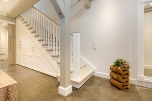 A staircase with white railings, a wooden planter with flowers, and a clean, modern interior. - AS1A - Old barn (AS) at c a l l s e n - appartements (Ummanz)