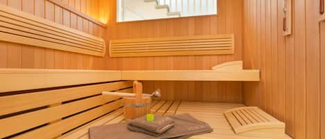 A sauna with wooden benches, a window, and a thermometer on the wall.