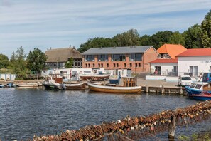 A marina with boats docked, a building with a red roof, and a white building with 'PEN' on it. - AS1A - Old barn (AS) at c a l l s e n - appartements (Ummanz)