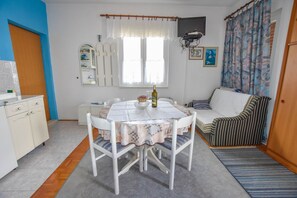 A compact living space with a dining area, a sofa, and a kitchen.