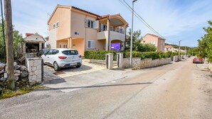 Una strada residenziale con case, un'auto bianca parcheggiata di fronte a una casa e un muro in pietra.