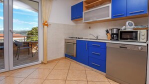 A kitchen with blue cabinets, a stove, oven, microwave, and a sink. - Apartments Ema (Razanj)