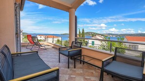 A balcony with a view of the sea, featuring a sofa, chairs, and a table. - Apartments Ema (Razanj)