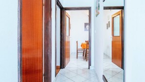 Un pasillo con puertas de madera y un comedor con mesa y sillas.