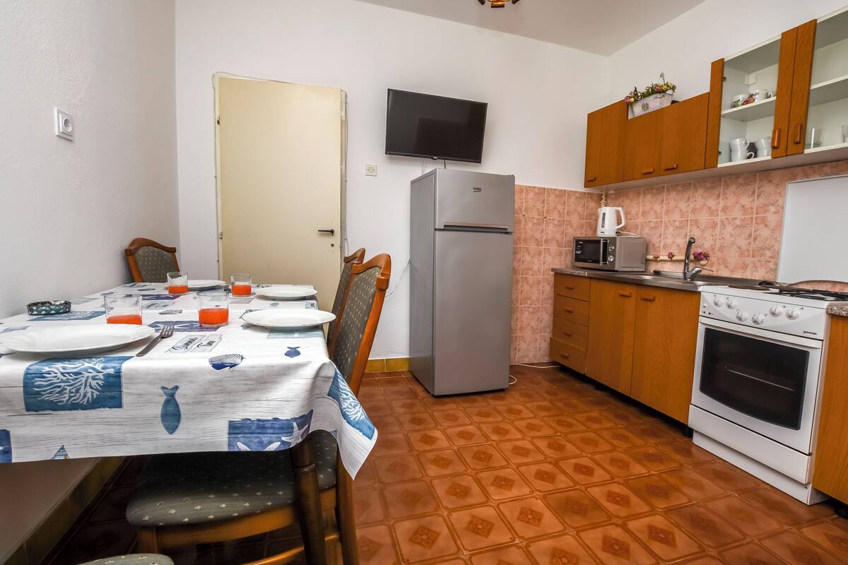 Cocina compacta con refrigerador, microondas, estufa y comedor con una mesa lista para dos.