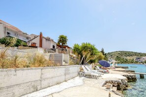 A coastal area with a concrete wall, lounge chairs, and a clear view of the sea.