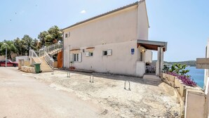 A building with a concrete ground floor, a staircase leading to the upper floor, and a view of the sea. - Apartments Apartmani Bebe (Razanj)