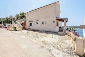 A building with a staircase, a small outdoor seating area, and a view of the sea.