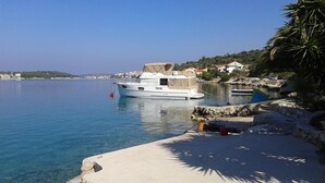 A marina with a white yacht docked at the pier, surrounded by calm water and a coastal town in the background. - Apartments Apartmani Bebe (Razanj)