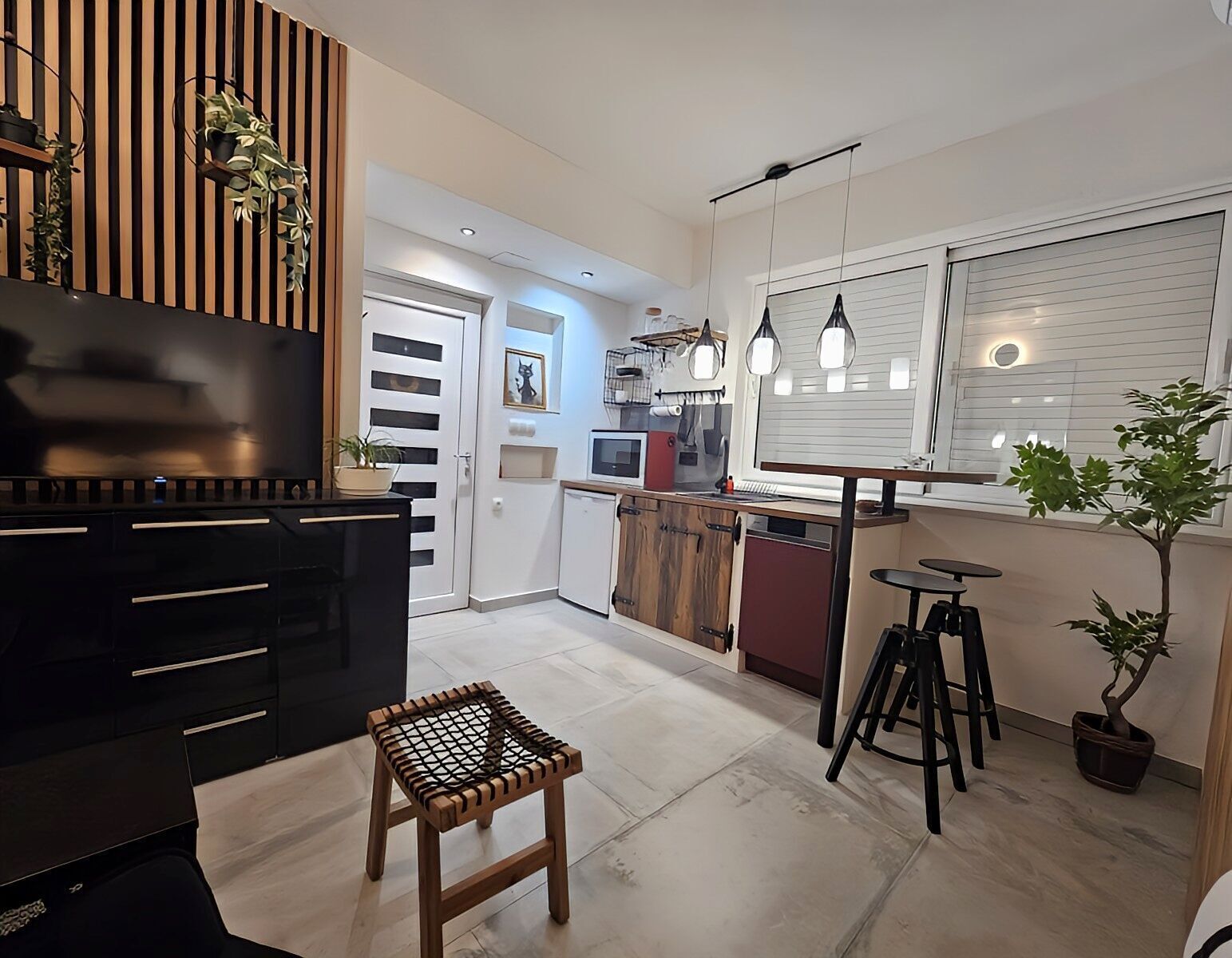 A modern kitchen with a wooden cabinet, a small stool, and a dining table with two chairs.