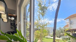 A room with large windows, a wooden table, and a potted plant. - Apartments Marijana (Vodice)