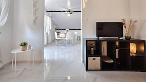 A modern living room with a TV, white furniture, and a ceiling fan. - Apartments Marijana (Vodice)