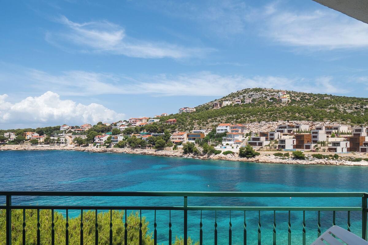 A coastal town with buildings on a hillside overlooking a clear blue sea.