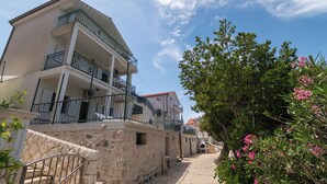 A multi-story building with balconies, a stone wall, and a narrow cobblestone street. - Apartments Ivica (Bilo)