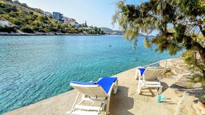 A seaside view with two sun loungers on a sandy beach, overlooking a calm sea. - Apartments Kresimir (Razanj)