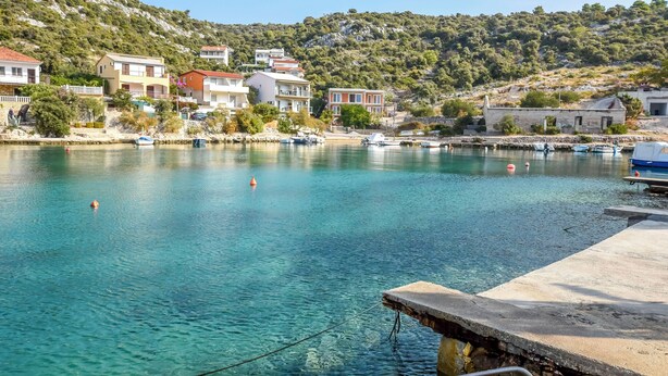 A coastal town with clear turquoise waters, a dock with boats, and buildings with balconies overlooking the sea. - Apartments Kresimir (Razanj)