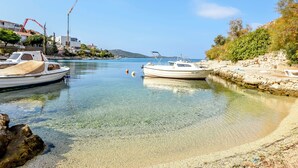 A marina with boats docked, clear water, and a stone wall on the right. - Apartments Kresimir (Razanj)