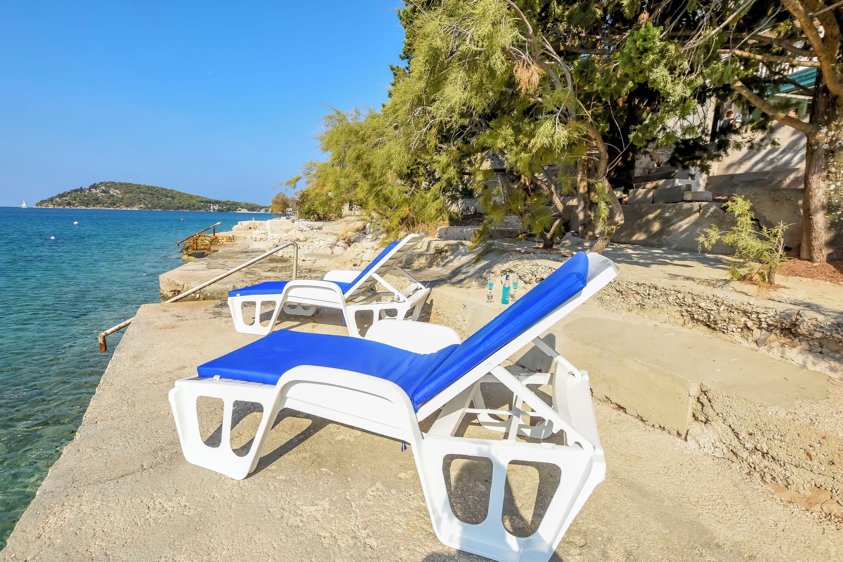 A seaside view with lounge chairs and a rocky shoreline.