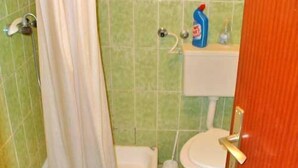 Une salle de bain avec une douche, des toilettes et un flacon de savon liquide sur le lavabo.