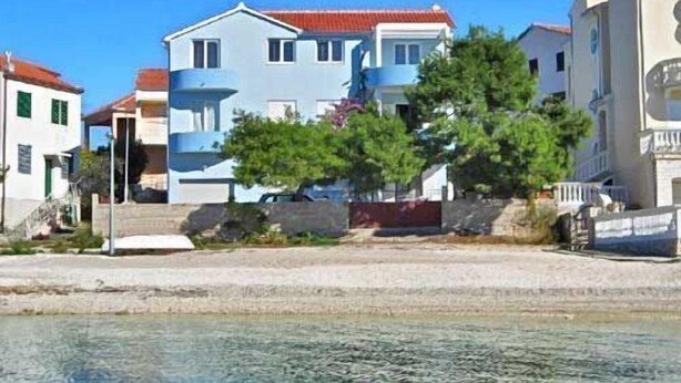 Un bâtiment situé sur la côte, avec un toit rouge, un balcon et une vue dégagée sur la mer.