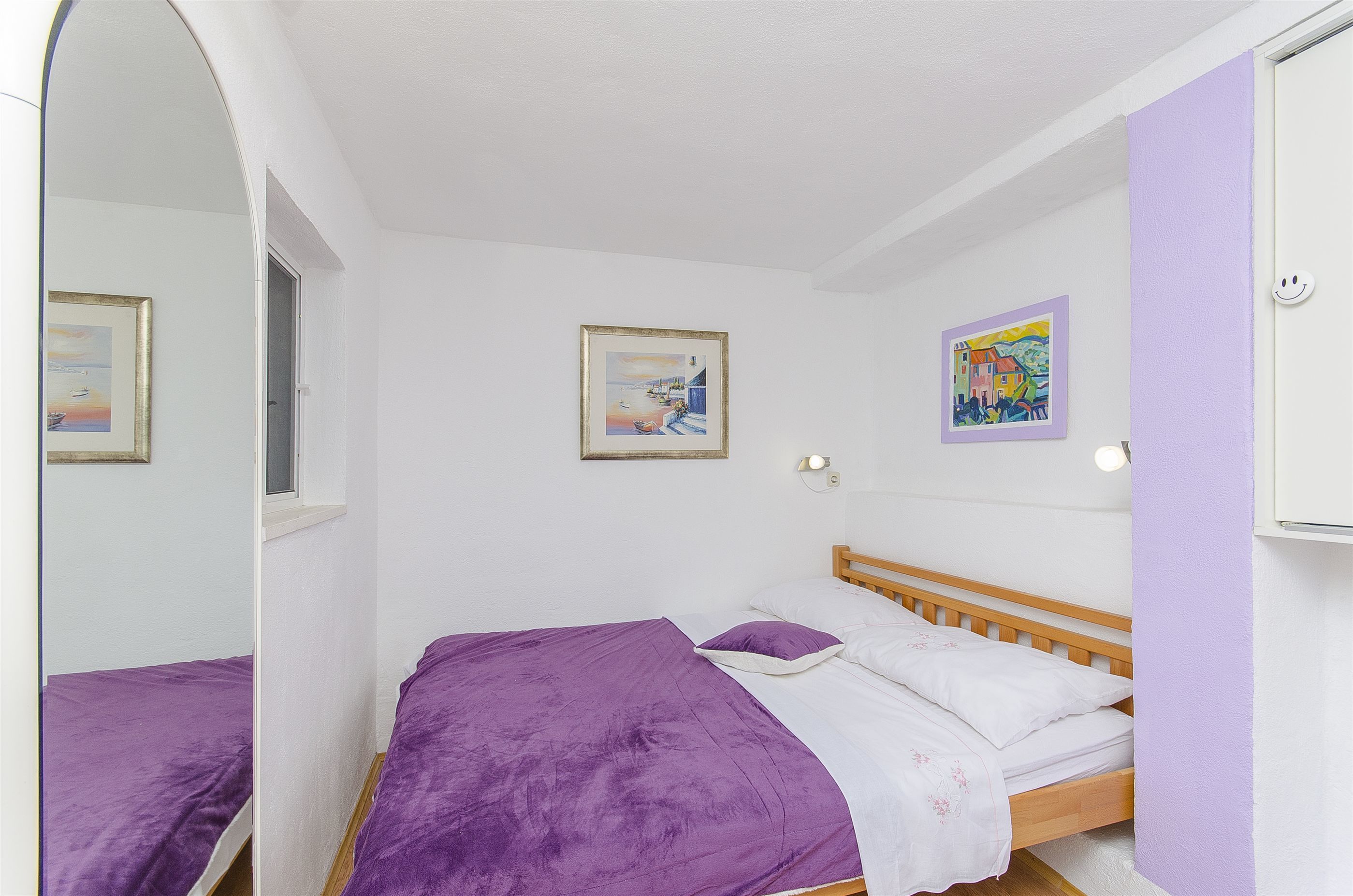 Un dormitorio con una cama, una ventana y dos cuadros en la pared.