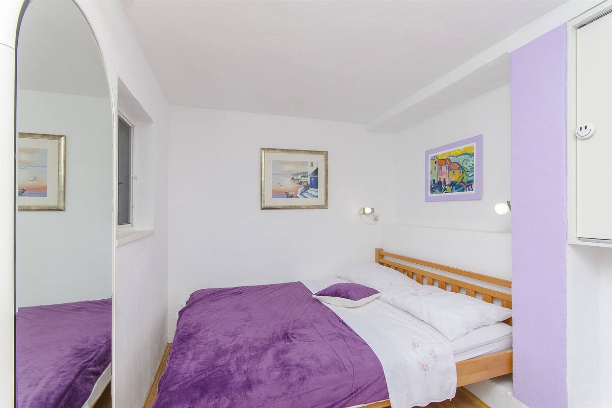 A bedroom with a bed, a window, and two framed pictures on the wall.