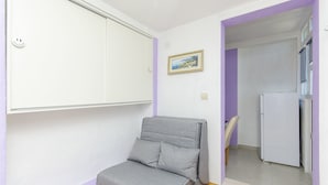 A small room with a grey sofa, a white wardrobe, a framed picture on the wall, and a white refrigerator. - Apartment Antonio (Bogomolje)