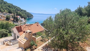 A coastal villa with a stone staircase, a red-tiled roof, and a view of the sea. - Apartment Antonio (Bogomolje)
