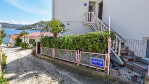 A white building with a staircase and a sign reading "NOVA VII". - Apartments Sopic (Rogoznica)